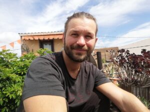 Junger Mann mit Haus im Hintergrund und blauem Himmel